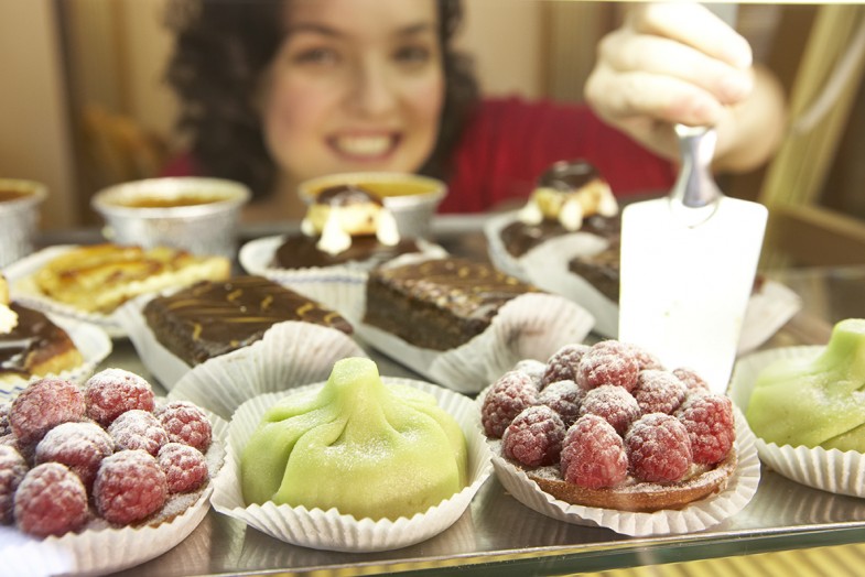 Woman putting fruit cakes on display, smiling, portrait, close-up