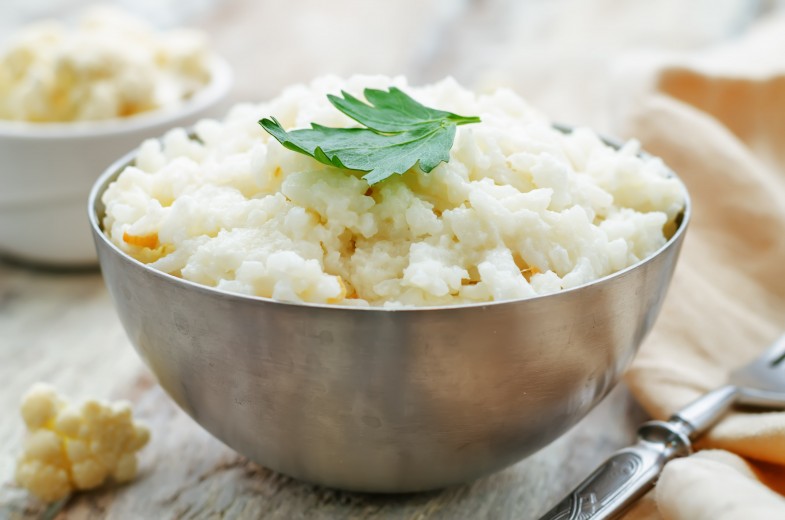 creamy cauliflower garlic rice on a white wood background. the toning. selective focus
